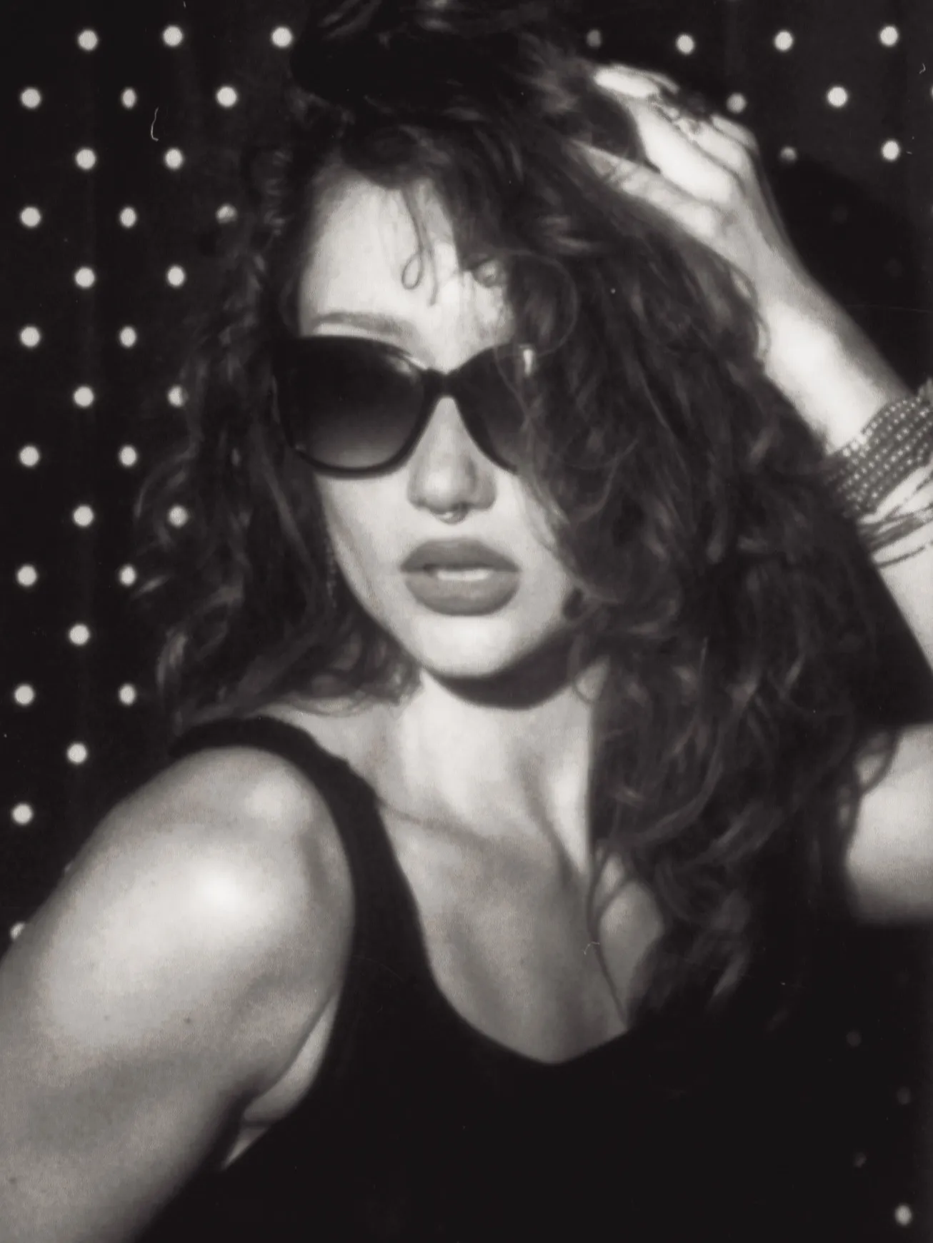 Enclosed photo booth black and white strip, frame three: a hand pushed into curly hair