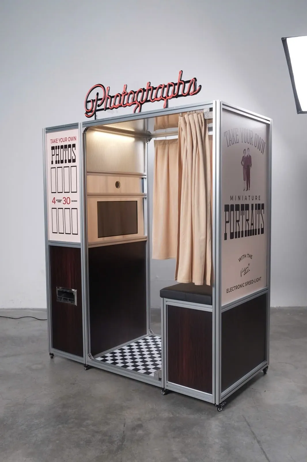 The Enclosed Booth: vintage enclosed photo booth with curtain, bench, checkerboard floor, and Photographs neon sign